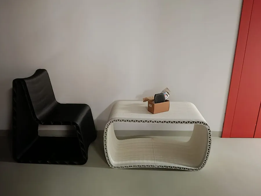 Il salottino DUKENA: una sedia nera e un tavolino bianco stampati in 3D in CoreLight3D®, appoggiati a una parete chiara