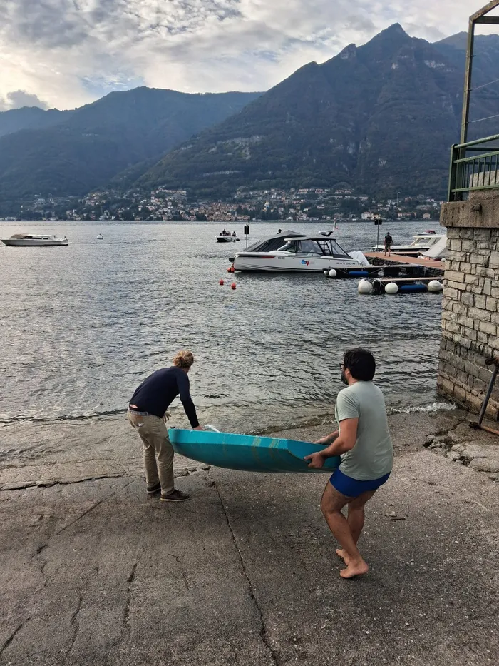 Two people carrying the hull to the water